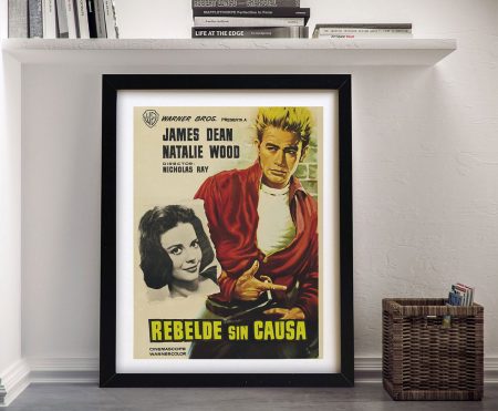Framed Rebel Without a Cause Spanish poster print featuring James Dean in red jacket and Natalie Wood, displayed against white wall