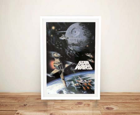 Framed Star Wars poster print featuring Death Star, X-wing and TIE fighters in deep space against a cream wall on timber floor