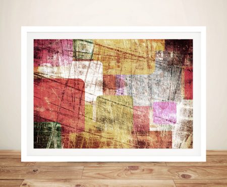 Urban Sprawl abstract framed print with red, mustard, pink and green textured blocks on a timber floor against a cream wall