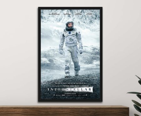 Framed Interstellar movie poster showing Matthew McConaughey in astronaut suit on icy planet, hanging above timber sideboard