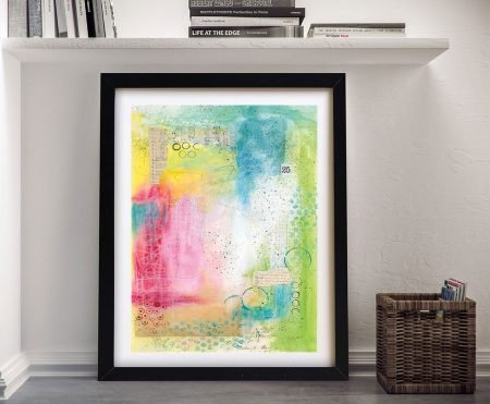 Collage 25 by Courtney Prahl framed print with pink, yellow, blue and green abstract mixed media leaning against white wall
