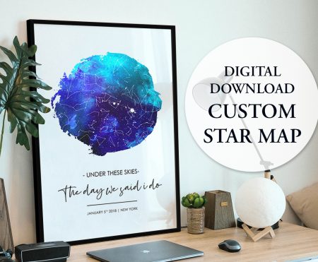 Black framed watercolour wedding star map propped on desk beside monstera leaf and moon lamp