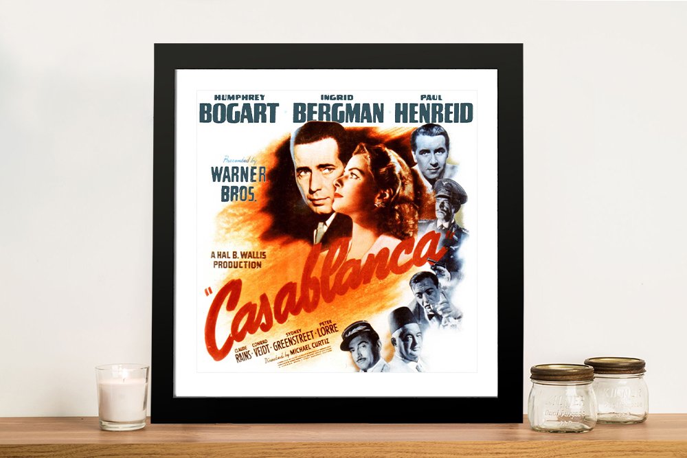 Framed Casablanca movie poster featuring Humphrey Bogart and Ingrid Bergman in vintage orange tones displayed on timber shelf