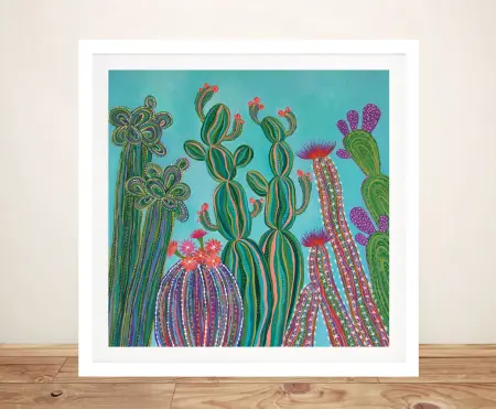 Vibrant cactus painting by Lisa Frances Judd in white frame, featuring teal background with green pink and purple cacti