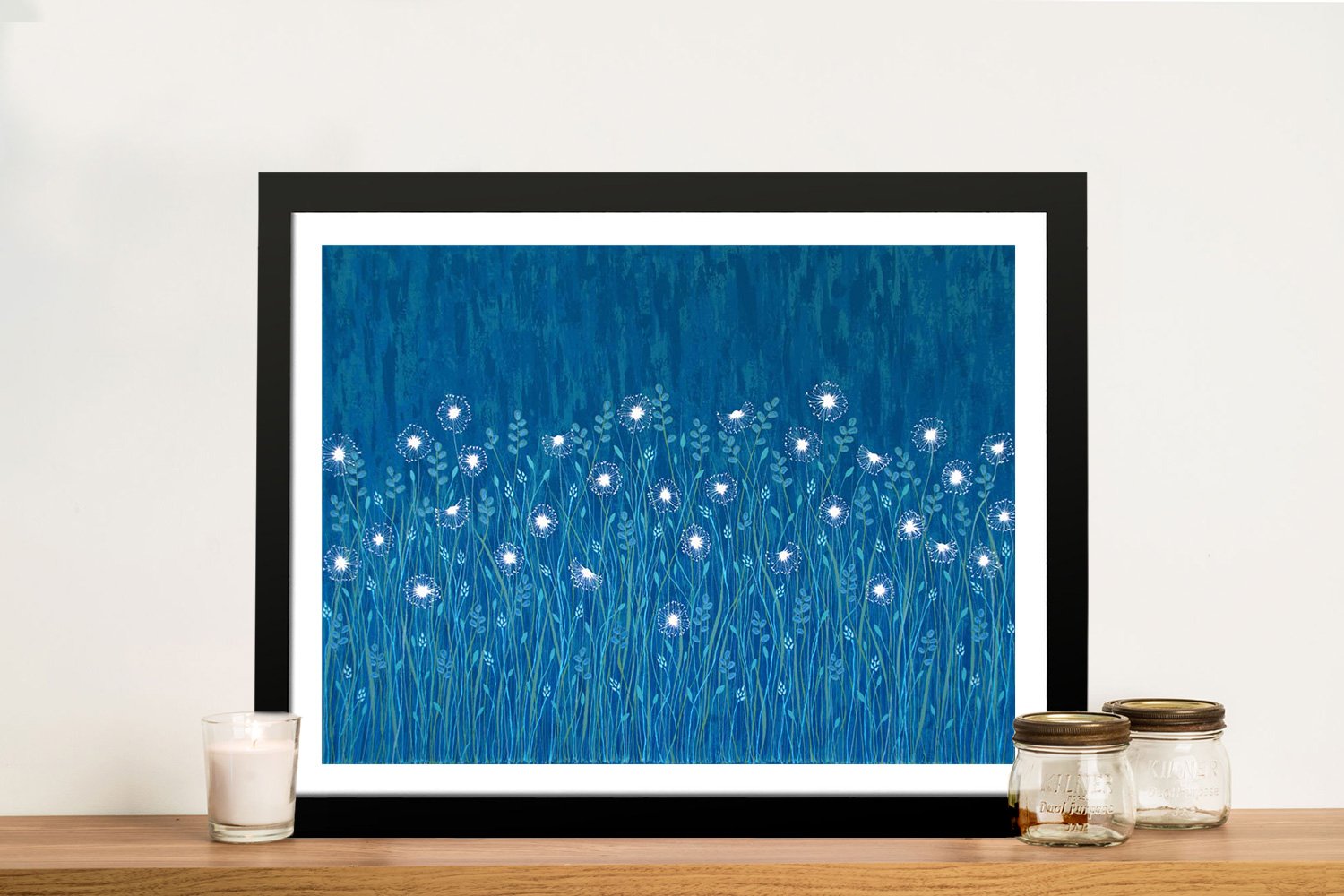 Dandelions on Blue framed print showing glowing white dandelions against deep teal background on a wooden shelf