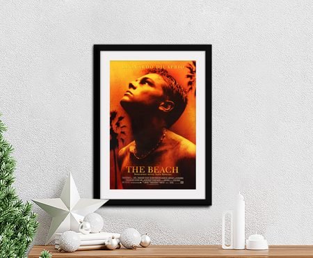 The Beach movie poster featuring Leonardo DiCaprio against a sunset-orange sky with palm trees, as a framed print