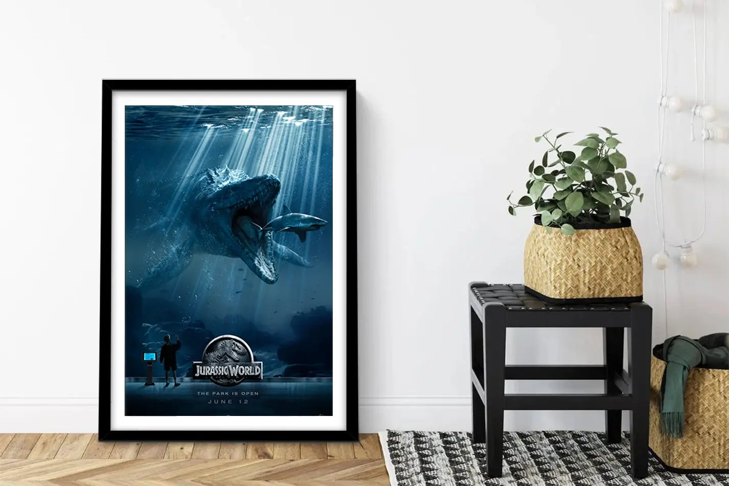 Framed Jurassic World movie poster showing underwater Mosasaurus dinosaur in deep blue, leaning against white wall beside black stool