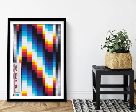 Felipe Pantone Posterzine framed print with pixelated rainbow geometric design leaning against white wall beside woven planter and stool