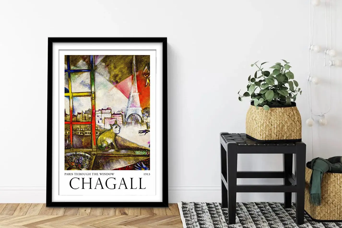 Black-framed Chagall Paris Through the Window contemporary art print leaning on a hallway floor by a potted plant