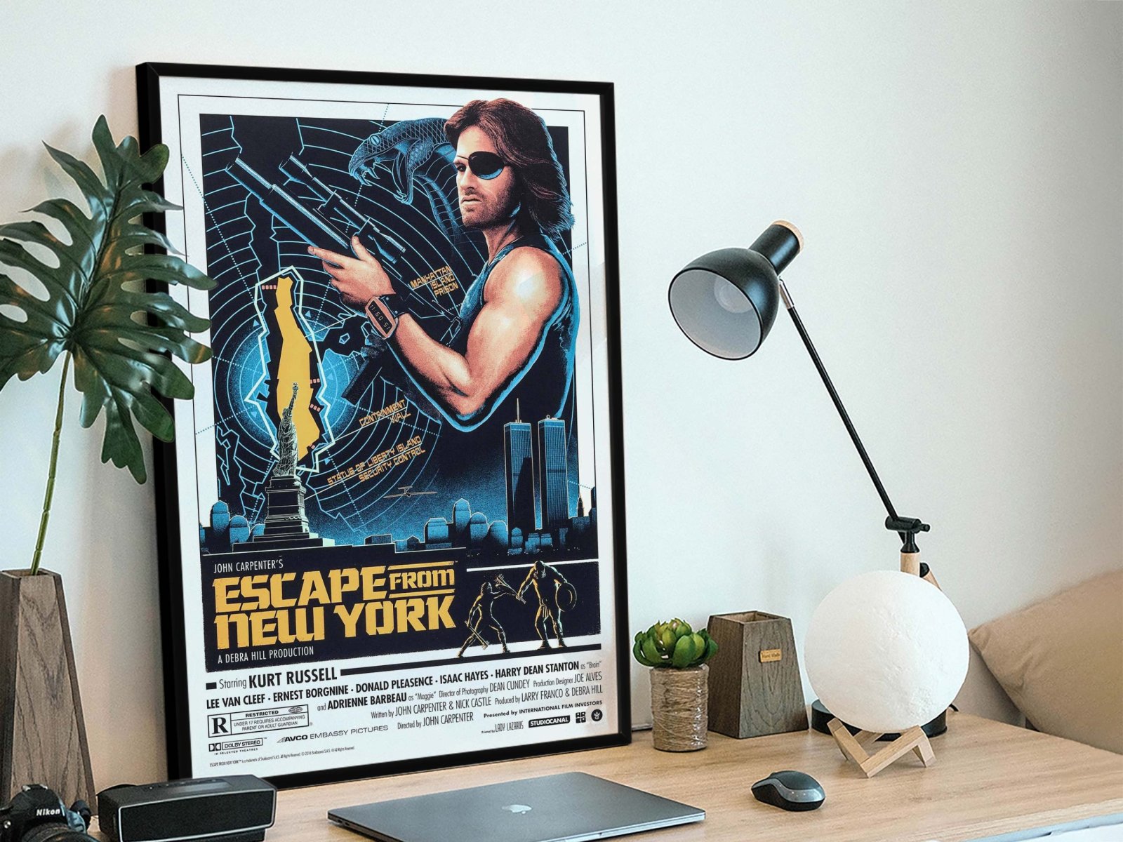 Escape from New York framed poster featuring Kurt Russell as Snake Plissken in blue and yellow tones on a desk