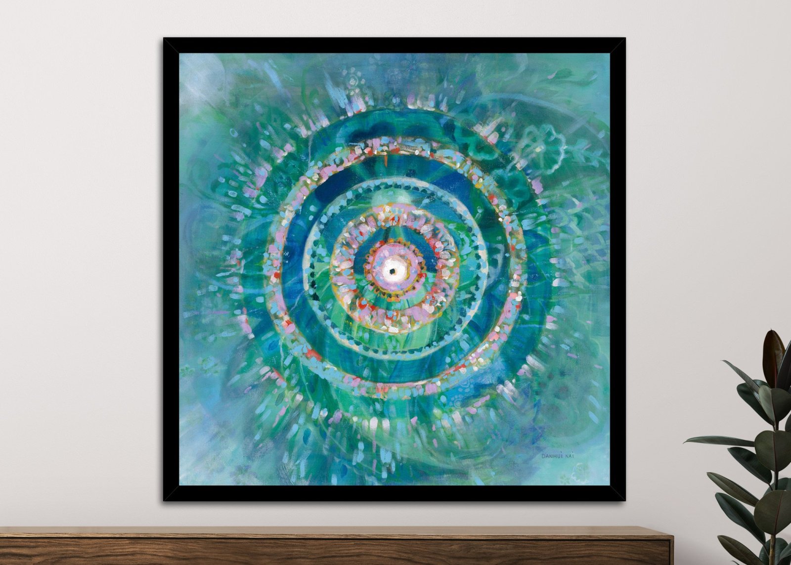 Danhui Nai Ocean Mandala framed print in black frame on neutral wall above timber console with green plant