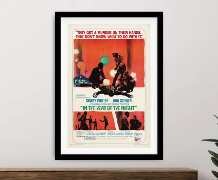 Black framed movie poster of In the Heat of the Night above a timber sideboard with a rubber plant