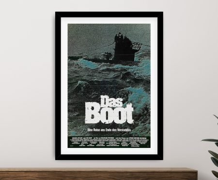 Framed German Das Boot movie poster on light grey wall above timber sideboard with green plant