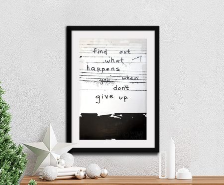 Black and white motivational typography print by Kent Youngstrom in black frame above Christmas styled console table
